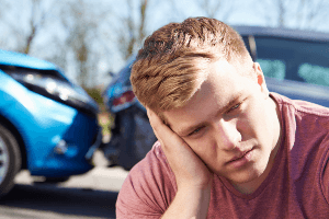 man sitting in front of crashed vehicle