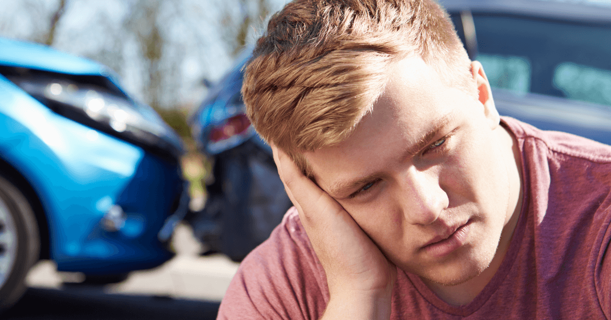 man sitting in front of crashed vehicle