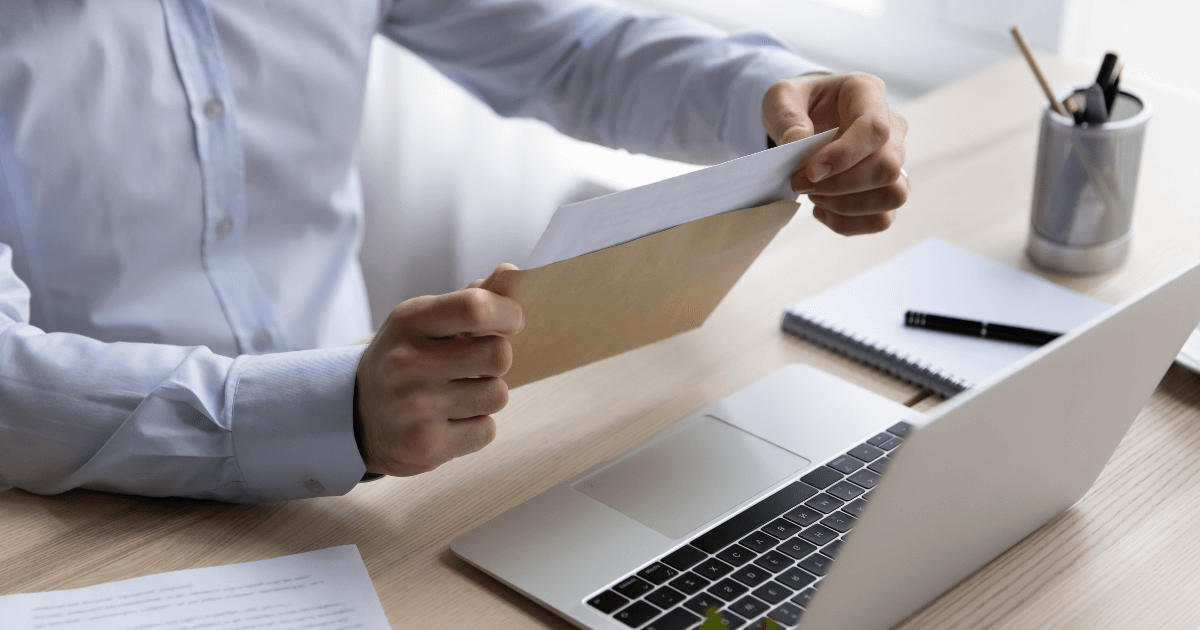 man opening a letter in front of his computer
