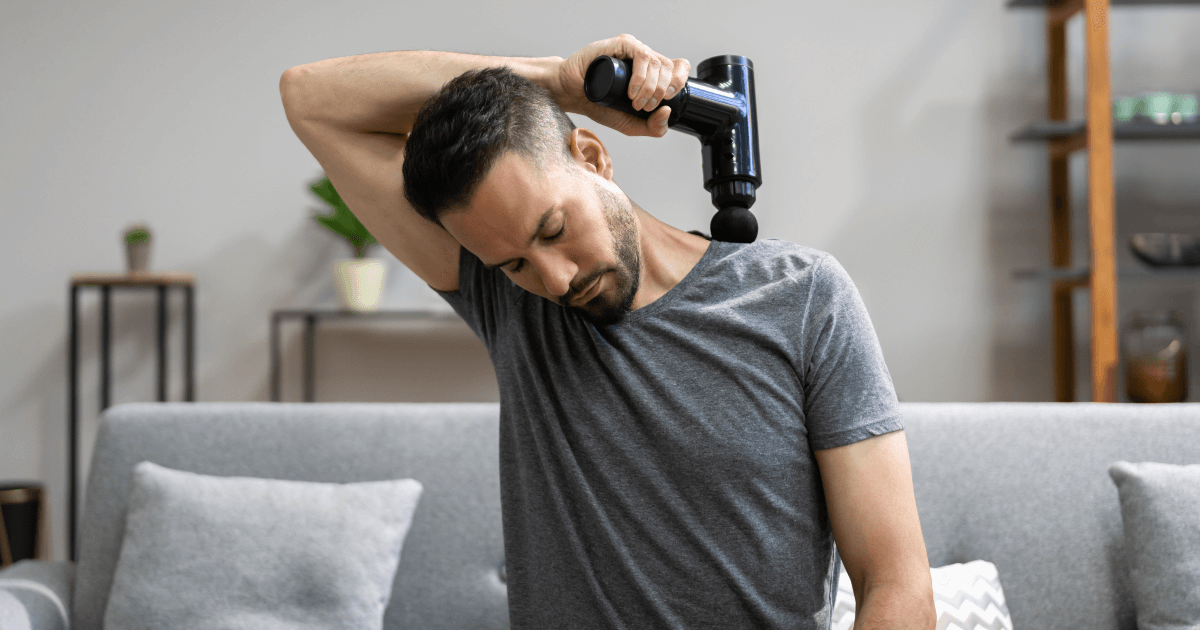 Man using massage gun on his own shoulder.